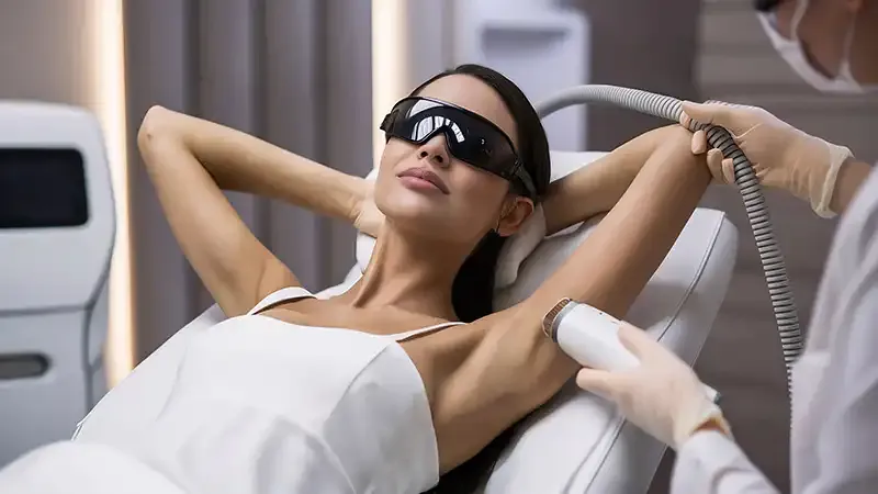 A woman wearing protective eyewear during a laser hair removal treatment on her underarm