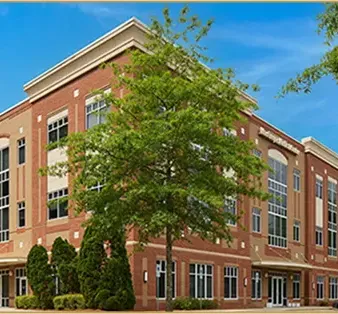 The exterior of the NOOR Dermatology & Aesthetics office building in Cary, NC, a brick medical office building with landscaping and parking.