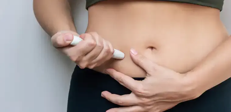 A woman holding an injection pen against her abdomen