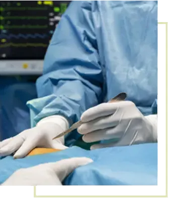 A gowned and gloved surgical team operating with a scalpel under sterile drapes, a patient monitor visible behind them.